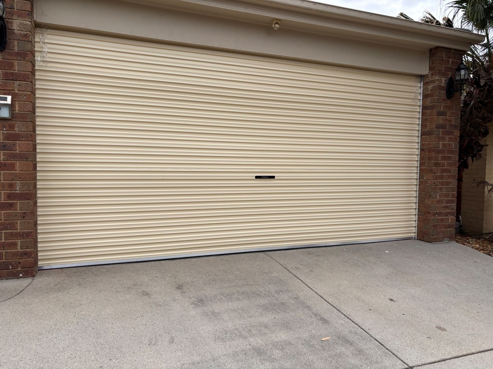 Cream roller garage door between brick pillars